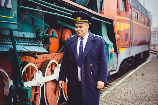 European or American train conductor is on his duty on a platform and other trains. Railway, steam trains, vintage trains .Train controller on the train, near a locomotive

