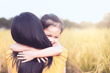 happy asian little child girl hugging her mother with love in the paddy field in vintage color tone