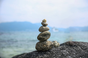 Colored stones balance on a background of blue sky and sea. Concept of balance and harmony