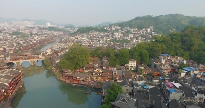 Top view or aerial shot of famous ancient town in Fenghuang County, China. Flying over Green River, hills and houses of the village. Travel,destination and world heritage concept.