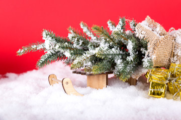 christmas tree lie on sledge and gold presents on white snow in winter