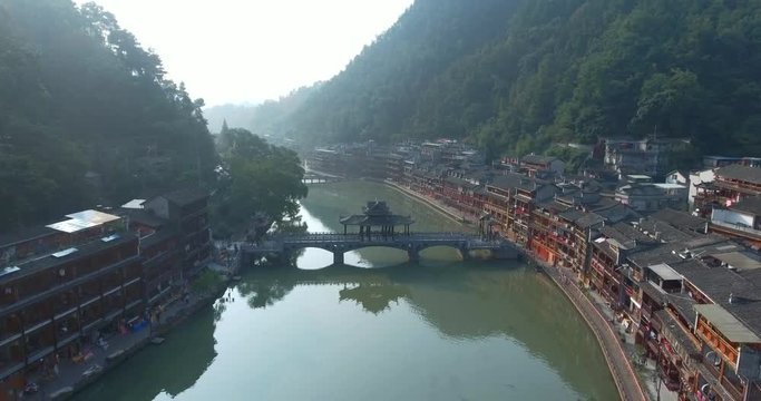 Top view or aerial shot of famous ancient town in Fenghuang County, China. Flying over Green River, hills and houses of the village. Travel,destination and world heritage concept.