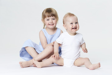 Funny brother and sister smiling in white studio