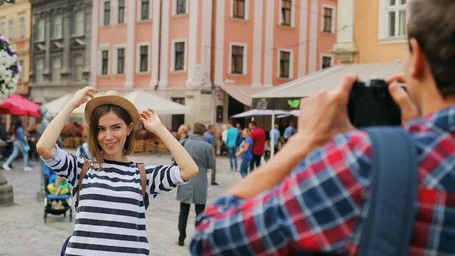 Happy urban couple taking photos on vacation. Boyfriend taking photo of smiling young girlfriend. Outdoors.