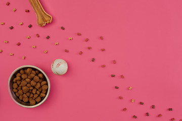 Dog snacks, dog chews, dog bone, ball toy for dog on a pink background with copy space