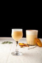 Two glasses with christmas eggnog drink decorated with cinnamon on dark background. Vertical composition.