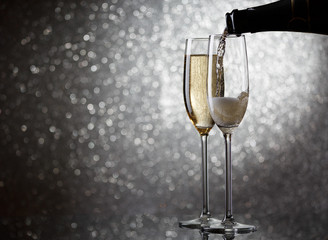 Image of bottle with pouring wine in wine glasses on gray background