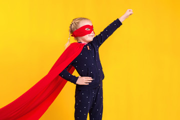 Superhero little girl in a red raincoat and a mask