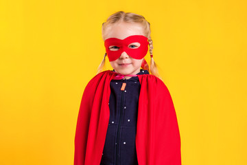 Funny little power superhero child girl in a red raincoat and a mask. Superhero concept.