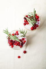 Perfect christmas cocktail: coconut margarita with cranberries and rosemary. Minimalistic concept. Linen cloth and white background. Vertical composition with copy space.