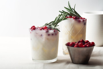 Perfect christmas cocktail: coconut margarita with cranberries and rosemary. Minimalistic concept. Linen cloth and white background. Horizontal composition with copy space.