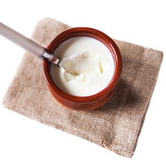 Sour  cream or  Cottage cheese curd in clay pot  isolated on a white background. Traditional Cuajada yogurt cream with a spoon.