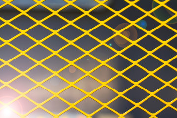 Yellow metal grid on the dark background, toned with sunlight