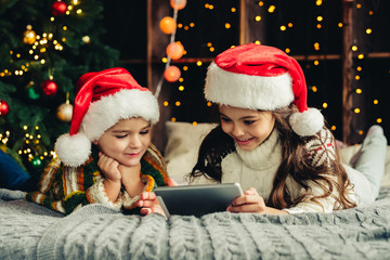 Fototapeta na wymiar Christmas holidays at home. Happy children using tablet, playing online, having fun.