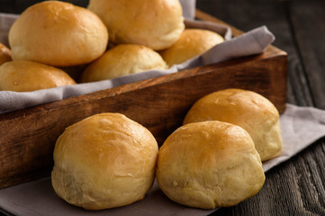 Homemade potato bread rolls on wooden tray.