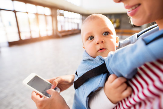Young mother with smartphone and baby travelling.