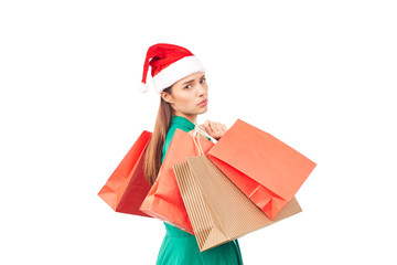 Studio portrait of young woman in Santa hat posing with shopping bags on white background