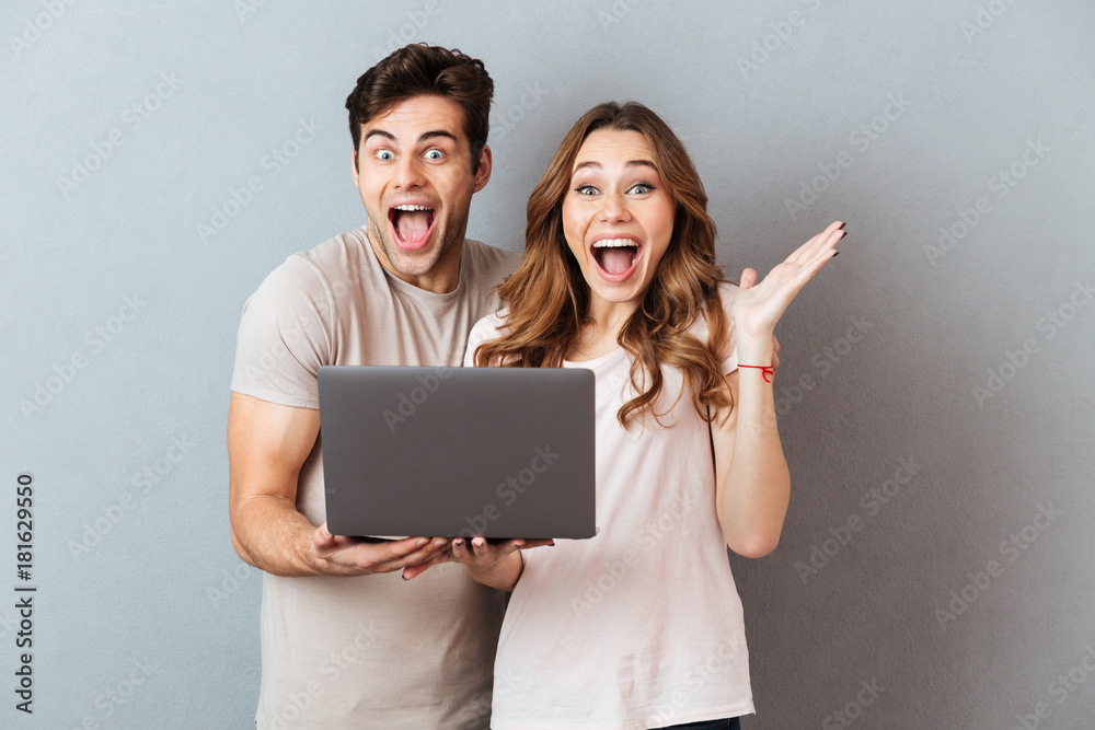 Sticker Portrait of an excited joyful couple holding laptop computer