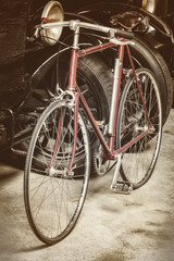 Fototapeta na wymiar Ancient rusted racing bicycle and black cars