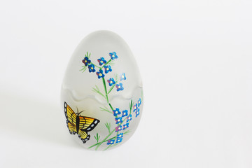Festive painted egg. Glass egg with painting. Easter egg decorated with a butterfly and flowers