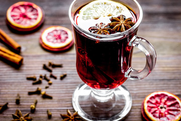 mulled wine with spices in cup on wooden background