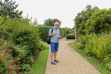 Are you coming with us? - old man with a gray beard and silver hair asks you a question on a path in a park. In a distance, an elderly couple can be seen. Concept: active elderly people.