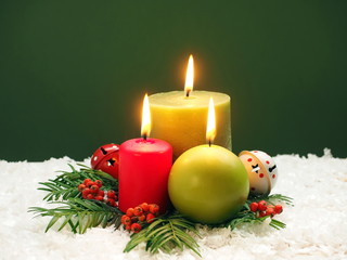 Christmas background with burning candles, fir tree and berries on green background