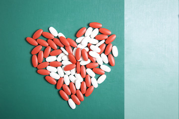 The heart made of tablets and pills on blue background