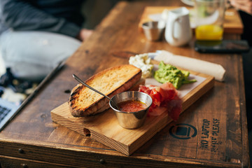 Typical spanish breakfast at hipster downtown cafe or restaurant, fresh bread toast with tomato spread, jamon cured ham and avocado, served on wooden cutting board, delicious and healthy