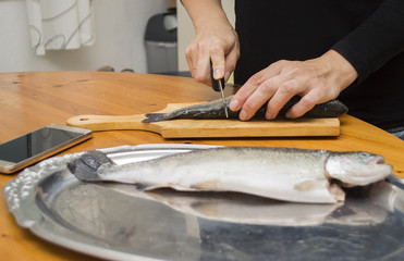 woman with a knife cut up the fish, scales, hands, cooking