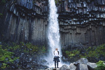 man tourist photographing on smartphone Svartifoss waterfall surrounded by basalt columns in the south of Iceland. Skaftafell national park in Iceland
