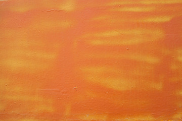 Fototapeta na wymiar The old orange background. Painted metal surface. The surface of the train as a background element. The metal is painted orange. Yellow streaks of paint on an orange background