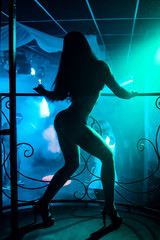 young girl with a slim sexy figure dancing go-go with a naked body in nightclub on stage