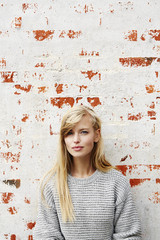 Stunning young blond lady in grey against wall, portrait