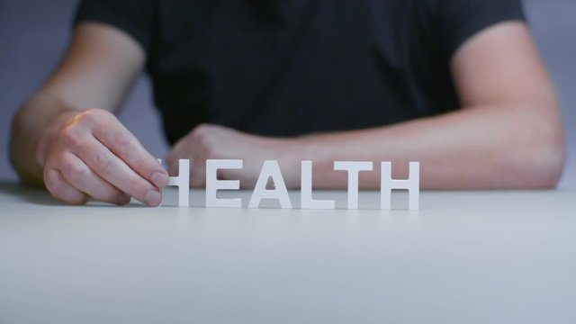 Man hands composition word health from white plastic letter on gray background