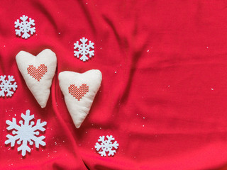 Two soft hearts and white snowflakes on a red background. Christmas background. Valentine's day background. Free space for text. Top view