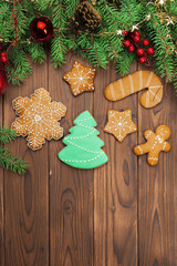 Christmas background with branch of fir tree decorated by gingerbread.