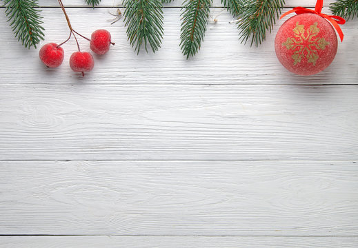 Christmas background. Branches of a Christmas tree, ball and small red apples on a wooden background.