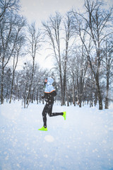 Man exercising / jumping and running in the park filled with snow.