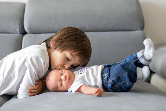 Sweet preschool boy, hugging with tenderness and care his little newborn brother