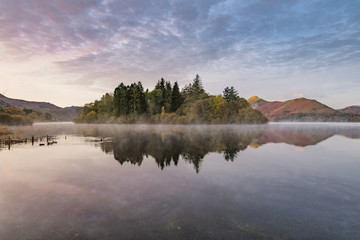 Beautiful calm reflections in a misty lake on a Autumn morning at Derwentwater in the English Lake District.