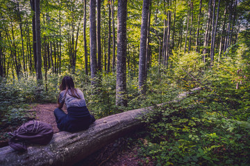 woman sitting on a tree in the woods and meditating