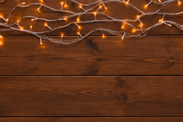 Fototapeta premium Christmas lights border on wood background