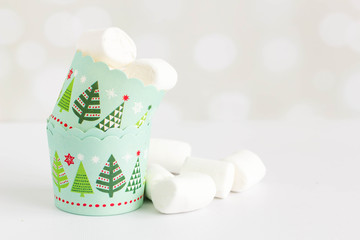 Marshmallows in christmas cupcake papers on white background, still life