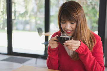 woman wear red sweater at restaurant. girl hold latte coffee cup at cafe