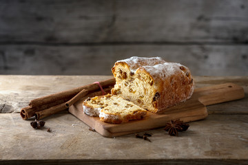 Christmas cake, in germany christstollen with cinnamon sticks and anise stars on a rustic kitchen table, wooden vintage background with copy space