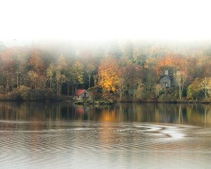 Boathouse on a calm lake with Autumnal colours and mist rising above tree's. Taken at Derwentwater...