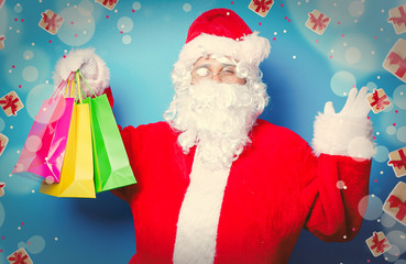Funny Santa Claus have a fun with shopping bags on blue background