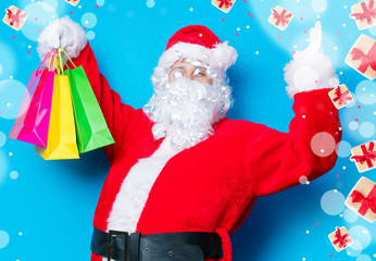 Funny Santa Claus have a fun with shopping bags on blue background