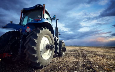 Foto op Plexiglas Een krachtige tractor behandelt de grond © VeremeeV_1980